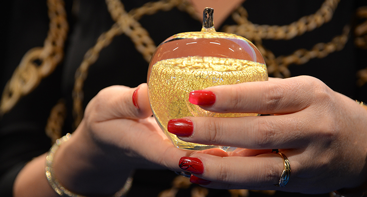 Guldäpplet som hålls av händer med långa röda naglar.