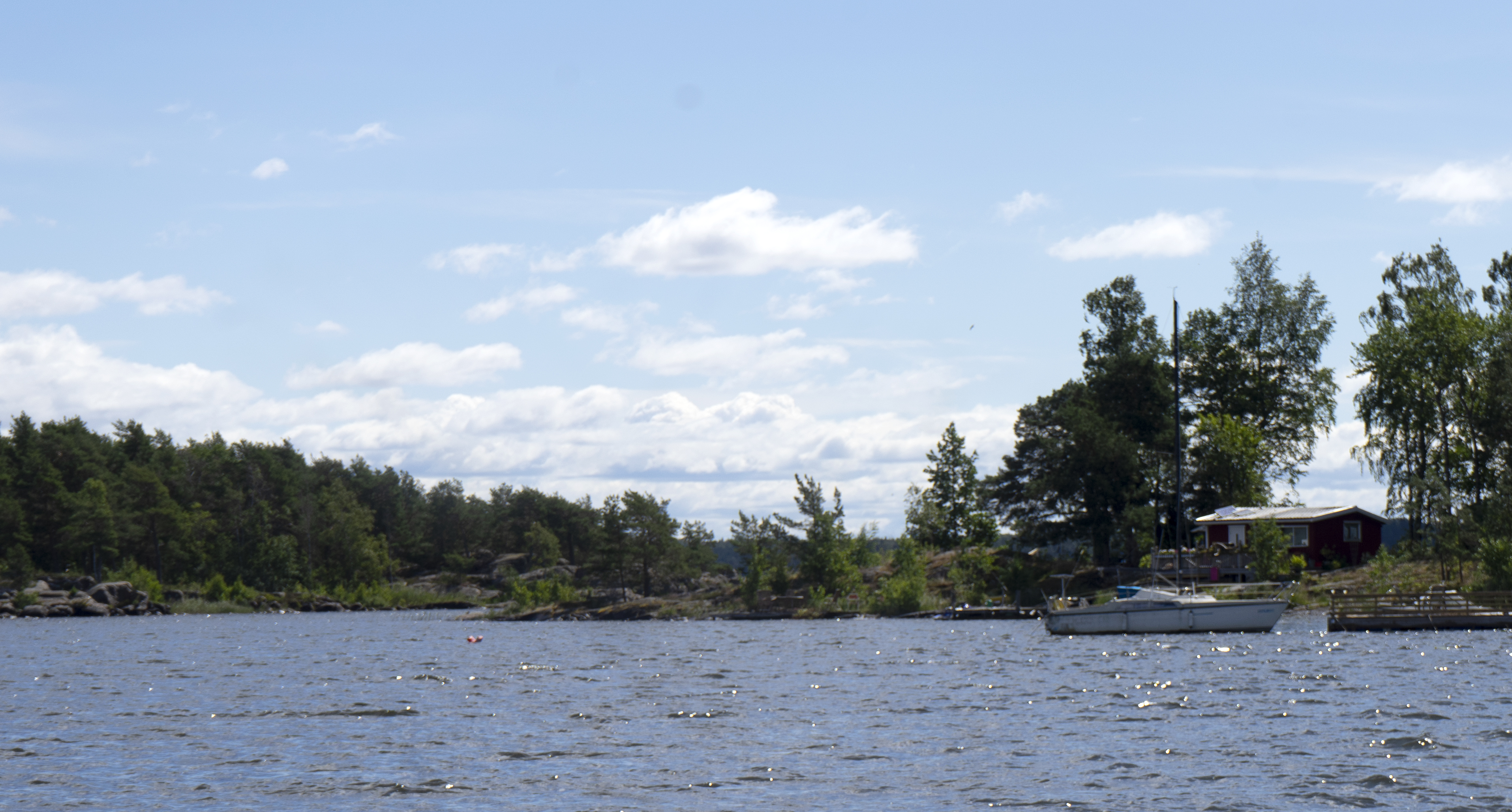 En ö med en båt vid brygga och liten sommarstuga. Bilden tagen på vägen ut mot Sööa från Mörudden.