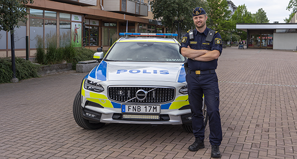 Polisen Anders framför en polisbil i Skoghalls centrum.